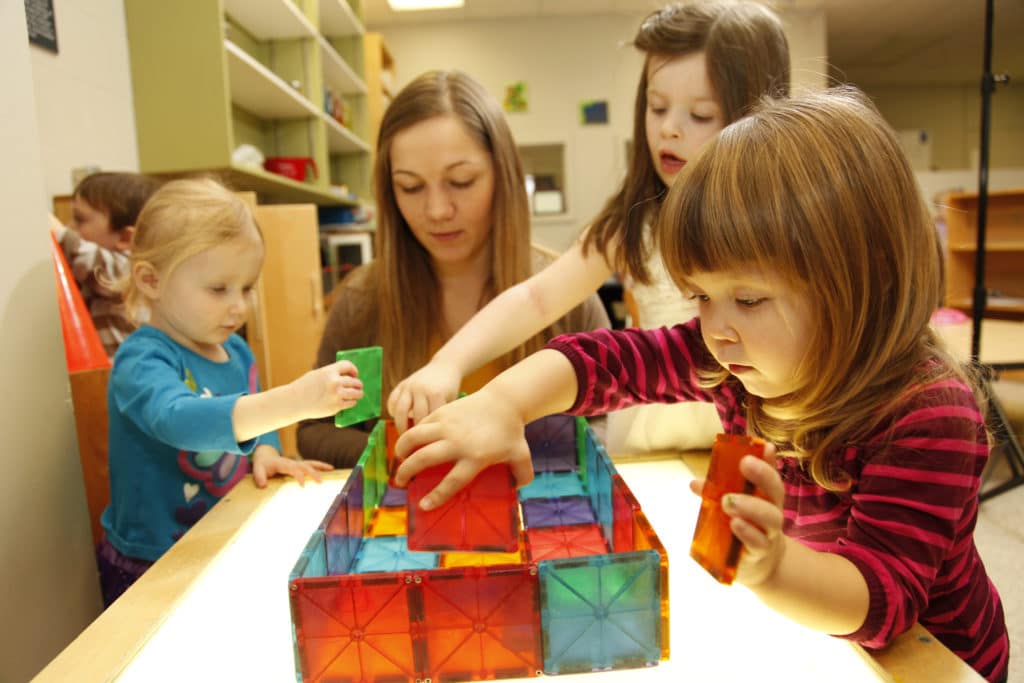 3 children in a learning setting building blocks with an ECE in nova Scotia